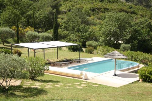 une piscine avec des tables et des parasols dans un jardin dans l'établissement Grande villa 230 m2 avec piscine et vue mer panoramique à proximité des Plages et du Circuit Paul Ricard, à Saint-Côme