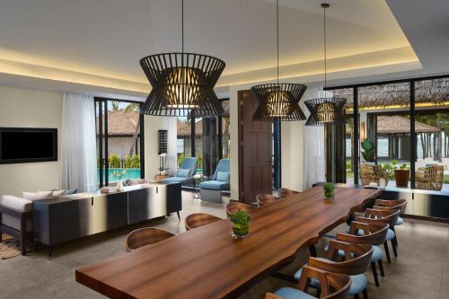 uma sala de estar com uma grande mesa de madeira e cadeiras em New World Phu Quoc Resort em Phu Quoc
