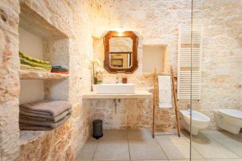 La salle de bains en pierre est pourvue d'un lavabo et d'un miroir. dans l'établissement Il Trullo Volza, à Locorotondo