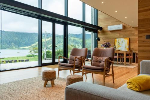 a living room with a table and chairs and windows at Sete Cidades Lake Cabin - Casa da Lagoa in Ponta Delgada