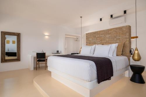 a white bedroom with a large bed and a mirror at Anna Platanou Suites in Agia Irini Paros