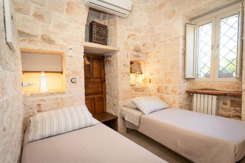 - 2 lits dans une chambre dotée de murs en pierre et de fenêtres dans l'établissement Il Trullo Volza, à Locorotondo
