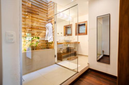 a glass shower in a bathroom with a wooden wall at Aldeia Jericoacoara - Suites Privativas in Jericoacoara