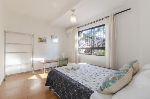 1 dormitorio con cama y ventana en Apartamento pé na areia em condomínio com piscina N1298, en Florianópolis