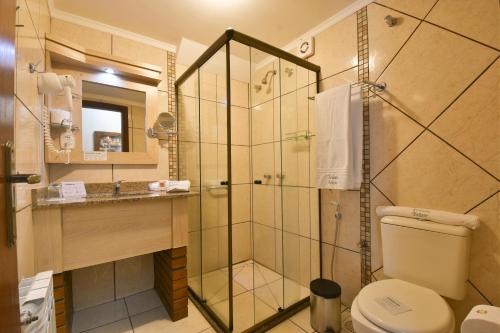 uma casa de banho com um chuveiro, um WC e um lavatório. em Pousada Belluno em Gramado