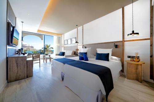um quarto de hotel com uma cama grande e uma sala de estar em H10 Costa Mogán em Playa del Cura