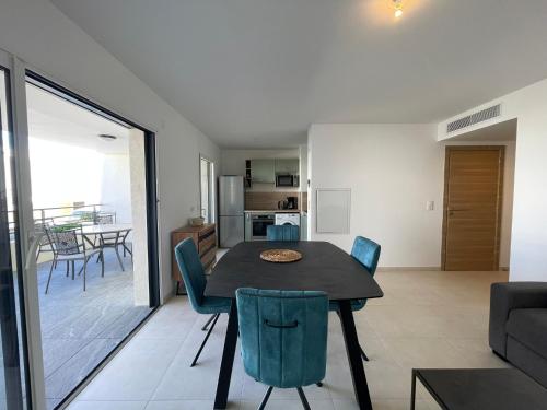a dining room and living room with a table and chairs at T2 dans une résidence neuve avec piscine in Calvi