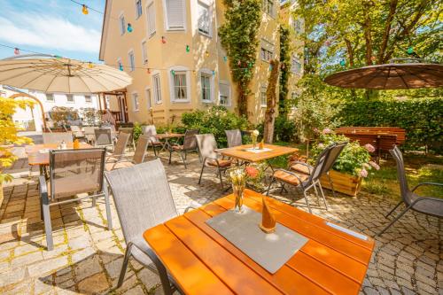 un patio al aire libre con mesas, sillas y sombrillas en Bavaria Lifestyle Hotel, en Altötting