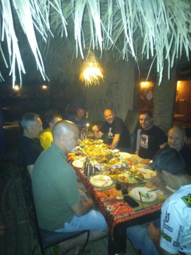 a group of people sitting around a table eating food at hostels Planet Sahara in Merzouga