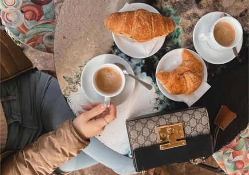 アッシジにあるSotto gli affreschi del 1800 con colazione inclusaの人がコーヒーカップとクロワッサンを持っている