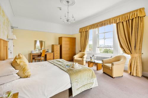 a bedroom with a bed and chairs and a window at The Falmouth Hotel in Falmouth