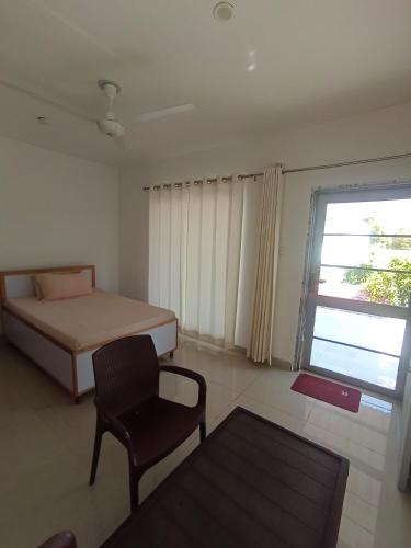 a bedroom with a bed and a chair and a window at Sir Mam Ashram in Bhaddi
