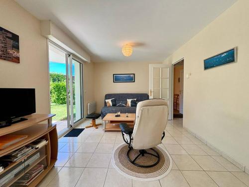 un salon avec une chaise et une télévision dans l'établissement Appartement 3 pièces Carnac – RDC avec terrasse, jardin, proche plage et commerces - FR-1-377-5, à Carnac