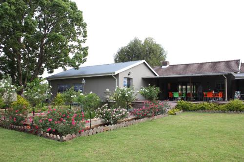 a house with a bunch of flowers in the yard at The Itumeleng Guest House in Bergville
