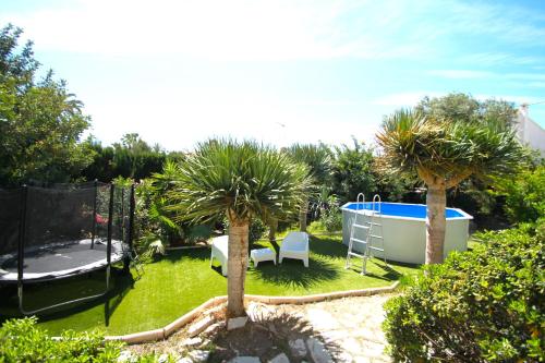 ogród z 2 palmami i basenem w obiekcie Chalet CasaTuris en Urb. La Font Sant Joan d´Alacant CH102 w mieście San Juan de Alicante