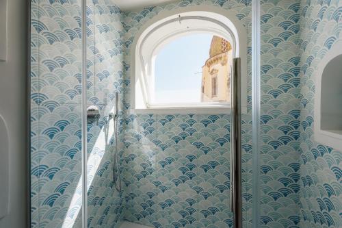 a bathroom with a shower with blue walls and a window at Proprietà Antonio 3 unità indipendenti in Positano