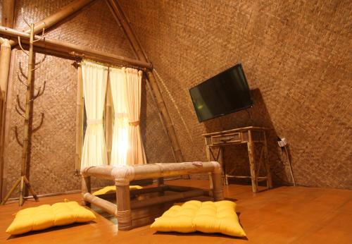 a living room with a tv and a chair and pillows at Villa ChavaMinerva Bambu - Lembang in Cikareumbi 2