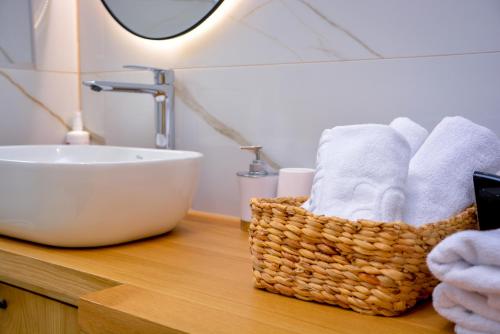 een badkamer met een wastafel en een mand met handdoeken bij Apartman Mona in Teslić