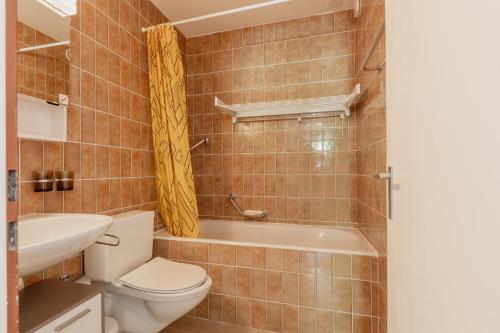 a bathroom with a toilet and a tub and a sink at Appartement proche des remontées mécaniques in Leukerbad