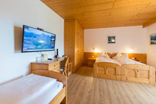 a bedroom with two beds and a flat screen tv at Hotel Dolomiten in Dobbiaco