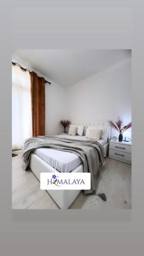 a white bedroom with two beds and a table at Himalayas in Gjirokastër