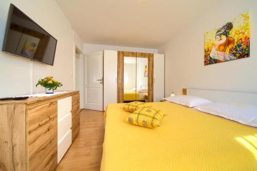 ein Schlafzimmer mit einem gelben Bett und einem TV in der Unterkunft Apartman Meri in Krk