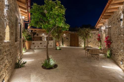 a courtyard with a tree and a table and chairs at St-Ten Stone Built Village in Áyioi Dhéka