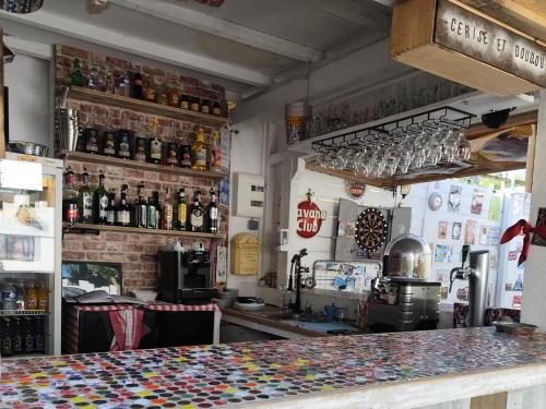 un bar con barra y algunas botellas de alcohol en HOULALA Gîte & Chambres d'hôtes, en Pont-Évêque