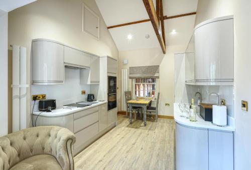 a kitchen with white cabinets and a table at The Apartment Garth House in Brampton