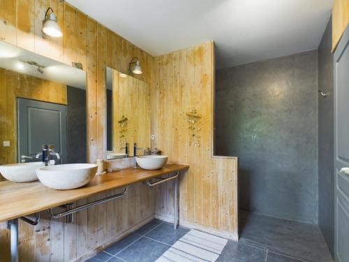 La salle de bains est pourvue de 2 lavabos et de murs en bois. dans l'établissement Piscine et sérénité pour votre séjour à Lanton, à Lanton