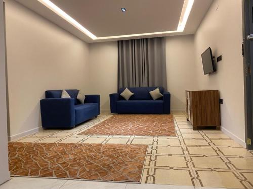 Sala de estar con 2 sofás azules y TV en كيان ألين en Abha