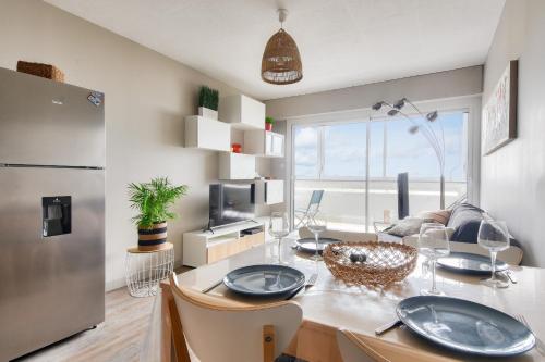 une cuisine et une salle à manger avec une table et un réfrigérateur dans l'établissement Vue sur mer et pieds dans l'eau, à Plage-des-Demoiselles