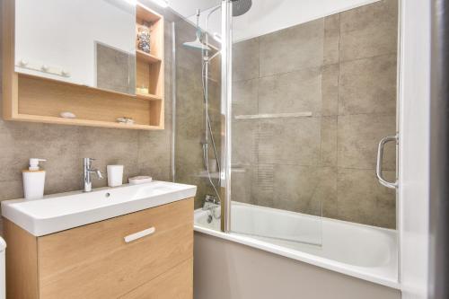 une salle de bain avec un lavabo blanc et une douche dans l'établissement Vue sur mer et pieds dans l'eau, à Plage-des-Demoiselles