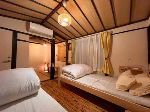 a bedroom with two beds and a window at Dormitory Omitsu in Nara