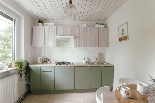 uma cozinha com armários verdes e brancos e uma mesa em Leśne zacisze - dom z kominkiem i balią em Jordanów