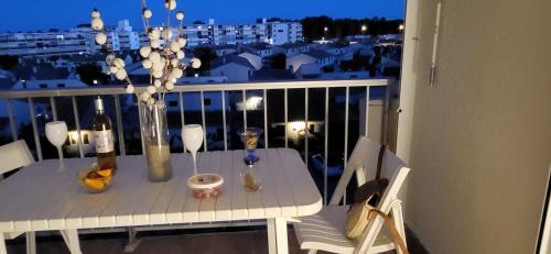 une table blanche avec un vase de fleurs sur un balcon dans l'établissement Petit Boudha climatisé Mezzanine rénové parking 400m plage 50m commerces, au Grau-du-Roi