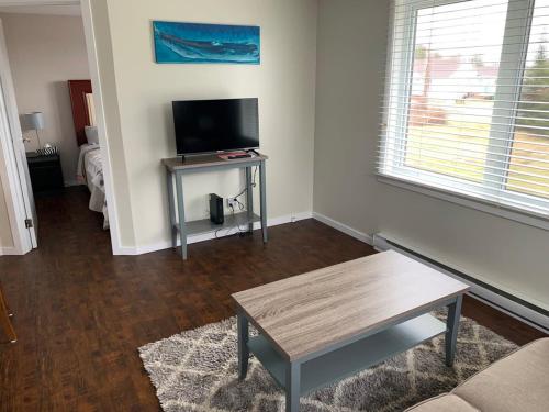 a living room with a table and a flat screen tv at Wild Cove Cabin in Twillingate