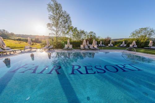 a swimming pool with chairs and a sign that reads all air resort at FAIR RESORT All Inclusive Wellness & Spa Hotel Jena in Jena