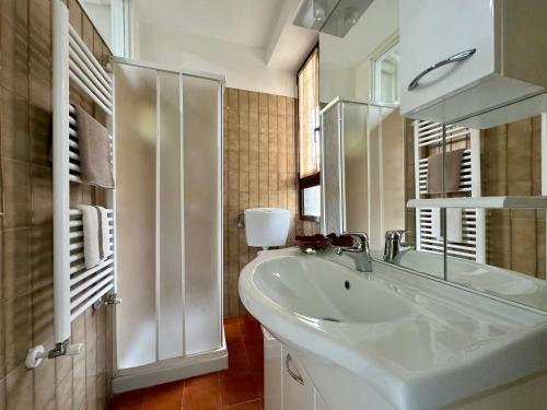 a white bathroom with a sink and a mirror at Verso il Lago in Laveno-Mombello