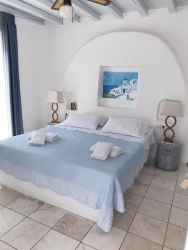 a white bedroom with a large bed with blue sheets at Sofia's Bungalows Mykonos in Mýkonos City