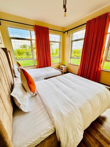 two beds in a bedroom with red curtains and windows at Lookout sirwa in Naivasha
