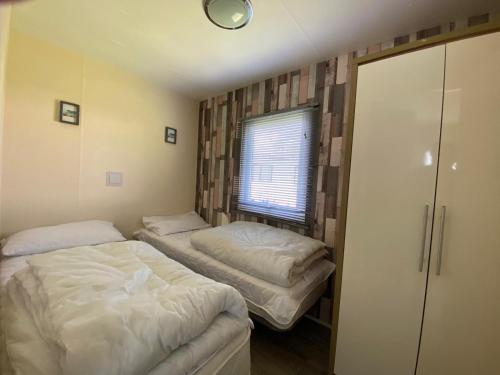 two beds in a small room with a window at Homely Caravan Just A Short Walk To Hembsy Beach In Norfolk Ref 00036ba in Hemsby