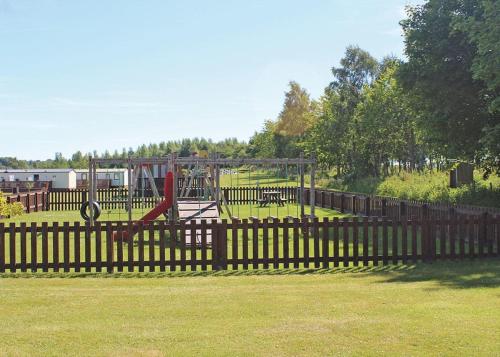 un parque con parque infantil detrás de una valla de madera en Nethercraig Holiday Park, en Alyth