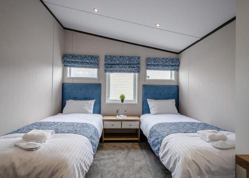 2 łóżka w małym pokoju z 2 oknami w obiekcie Green Meadows Country Park w mieście Harker