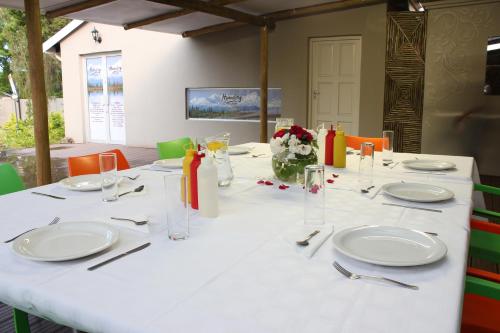 a long white table with plates and utensils at The Itumeleng Guest House in Bergville