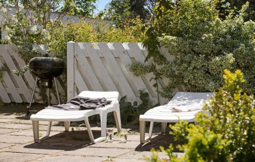 two white chairs and a grill in a yard at Cozy Home In Knebel With Sauna in Knebel