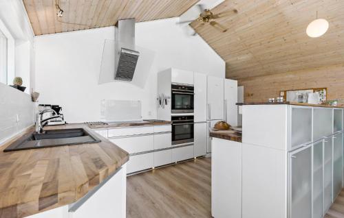 a kitchen with white cabinets and a wooden ceiling at Cozy Home In Knebel With Sauna in Knebel