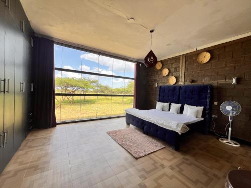 una camera con un letto blu e una grande finestra di Amboseli Glass house a Oloitokitok 