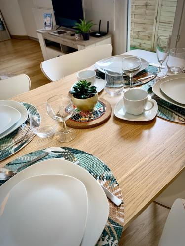 une table en bois avec des assiettes blanches et des verres dessus dans l'établissement Studio Océan Remblai, à Les Sables-dʼOlonne