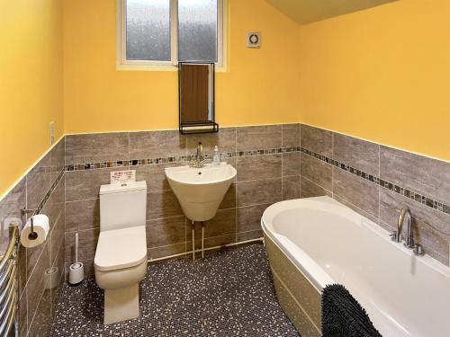 y baño con aseo, lavabo y bañera. en The Stables en Forncett Saint Mary